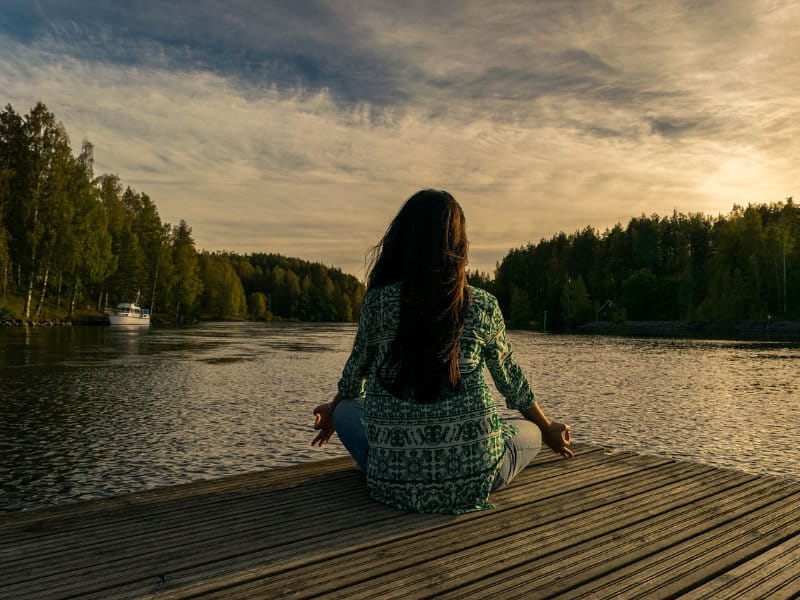 eine Frau Sitz am See und Meditiert